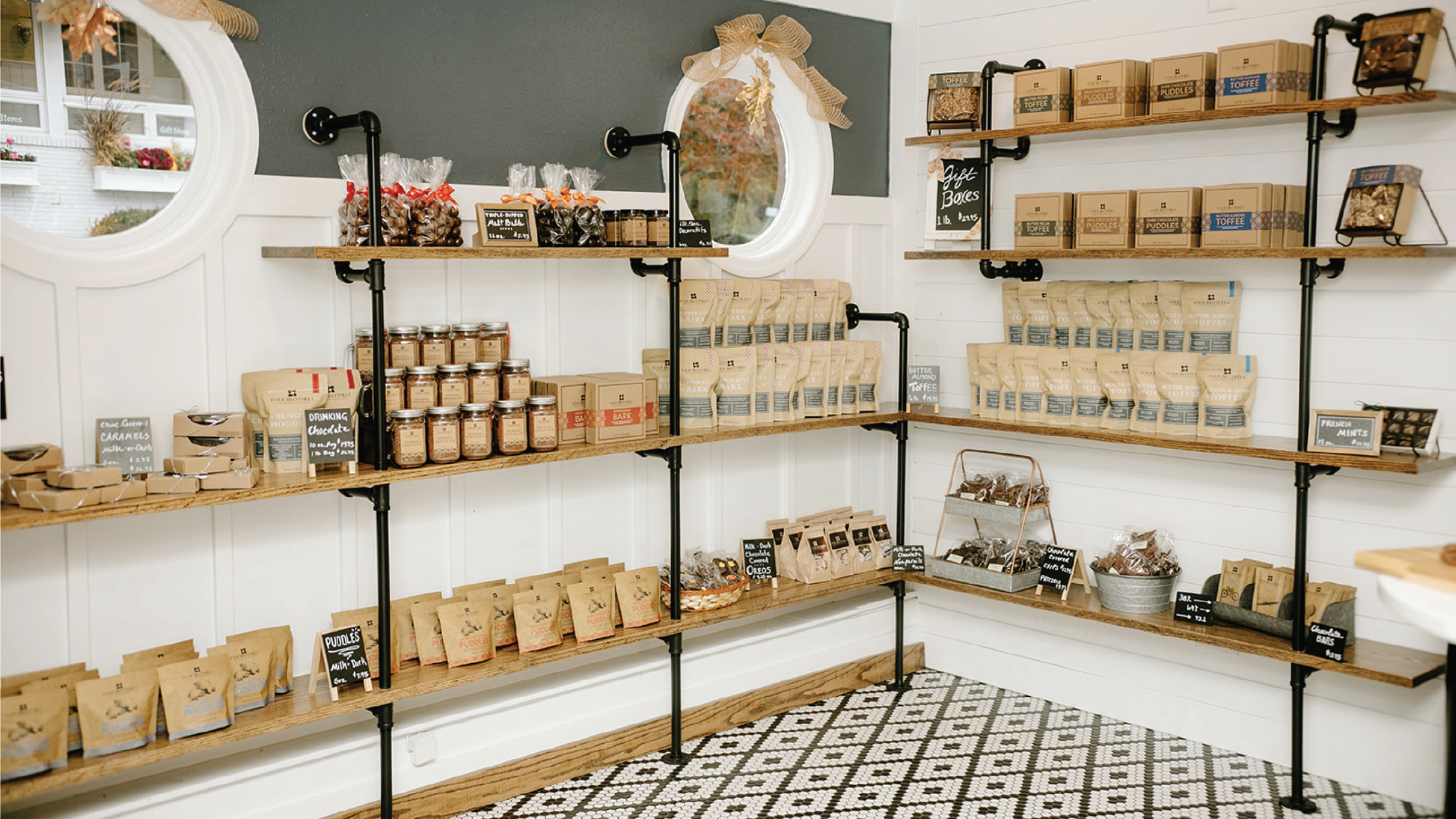 The inside of Four Brothers Fontana Store with a checkered tile floor, wooden shelves with handcrafted chocolates such as butter almond toffee, and peppermint bark displayed.